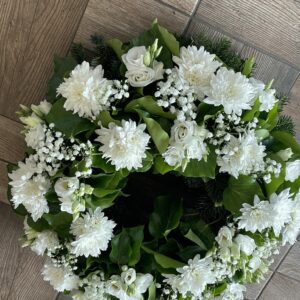 Fehér krizantémok, liziantuszok és rezgő virágok alkotta görög koszorú.