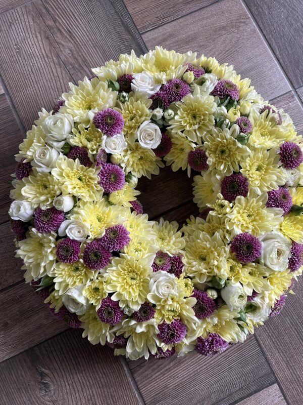 Fehér gerbera, rózsa és lila krizantém görög koszorúban