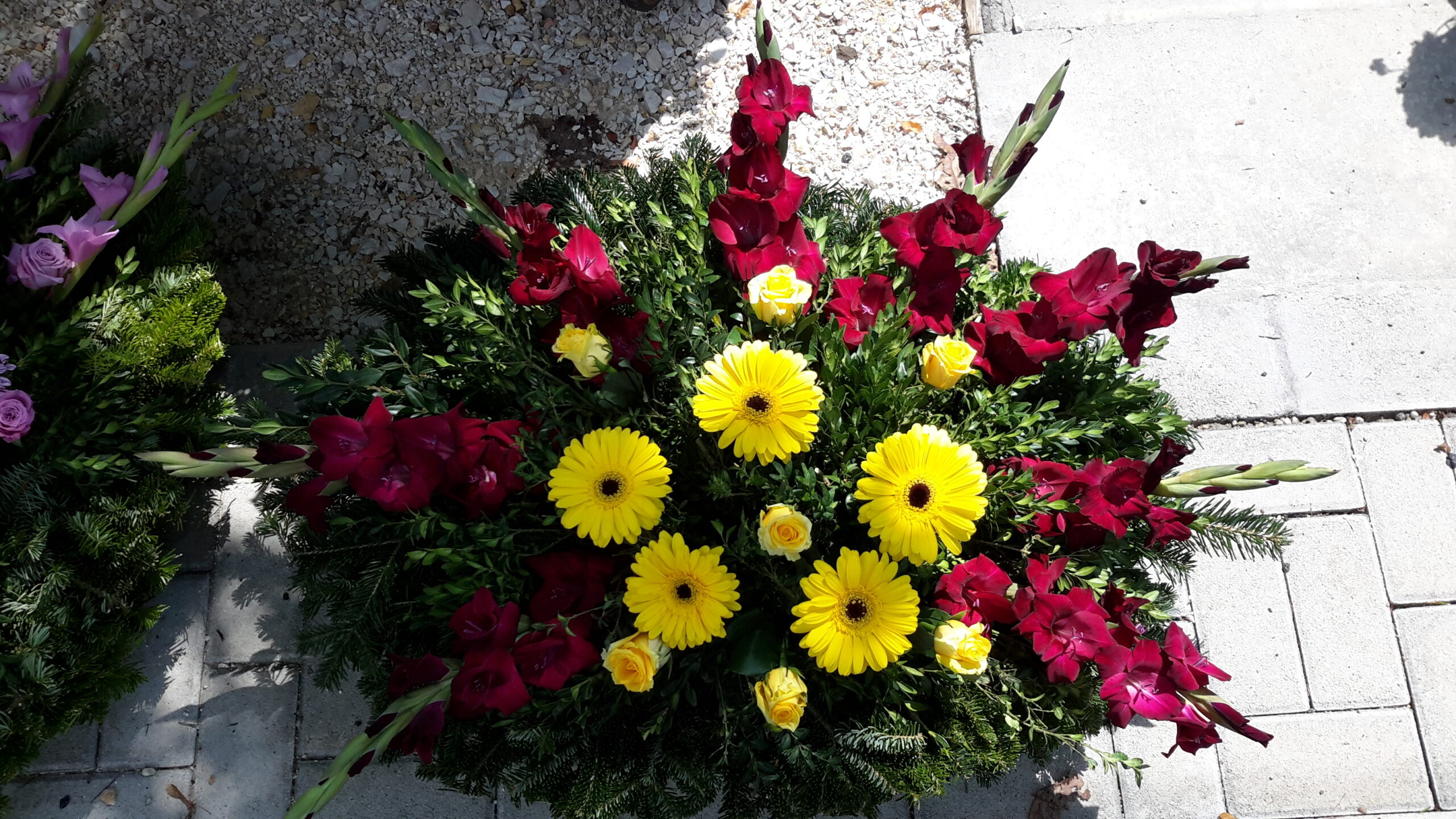Napfény és Szenvedély - Középen sárga gerbera és rózsa, szélén vörös kardvirágok Fekvő Koszorú