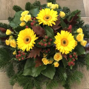 Napsugár Szerenádja - Sárga Gerbera, Sárga Rózsacsoport és Piros Bogyókkal Díszített Fekvő Koszorú